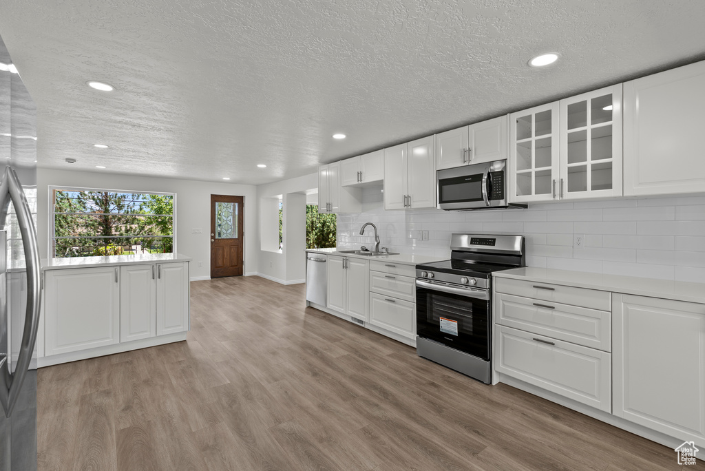 Kitchen with appliances with stainless steel finishes, light countertops, recessed lighting, light wood-style flooring, and a textured ceiling