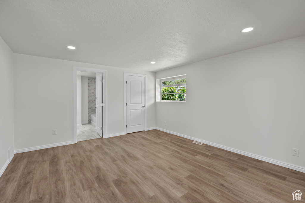 Unfurnished room with light wood finished floors, recessed lighting, and a textured ceiling