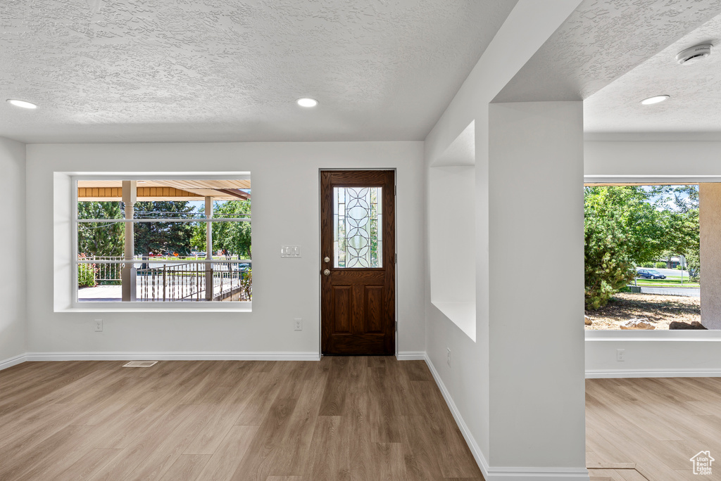 Entrance foyer featuring a textured ceiling, wood finished floors, and recessed lighting