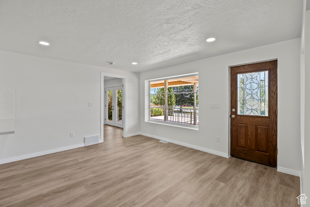 Foyer with a textured ceiling, light wood finished floors, and recessed lighting