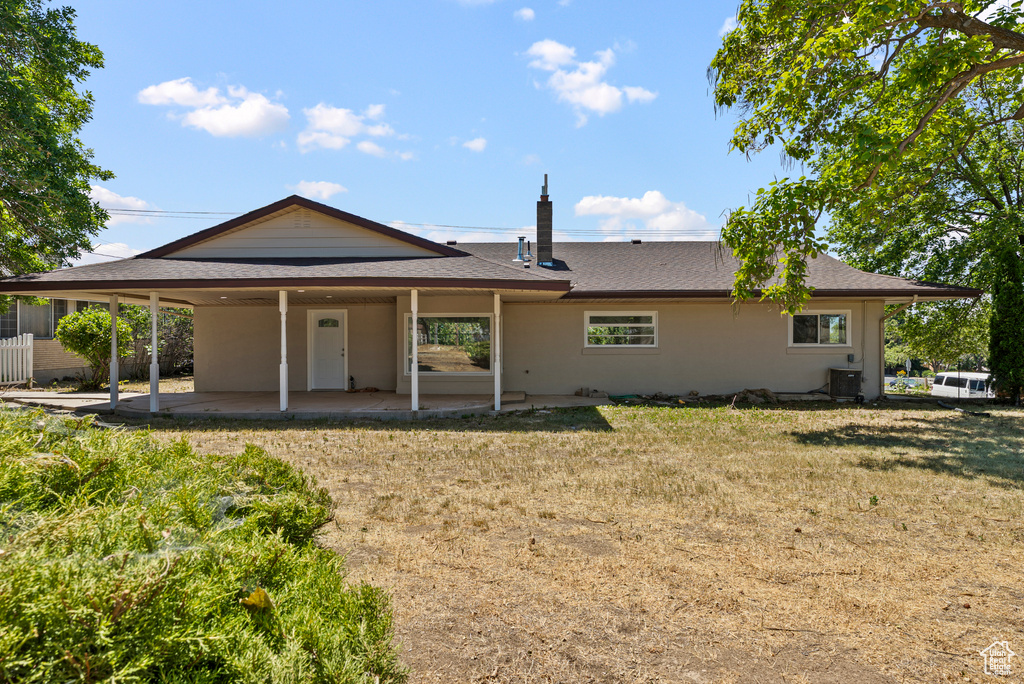 Back of house with a patio, a carport, and a shingled roof