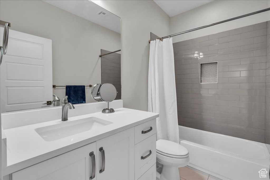 Bathroom featuring vanity, shower / bath combination with curtain, and tile patterned flooring