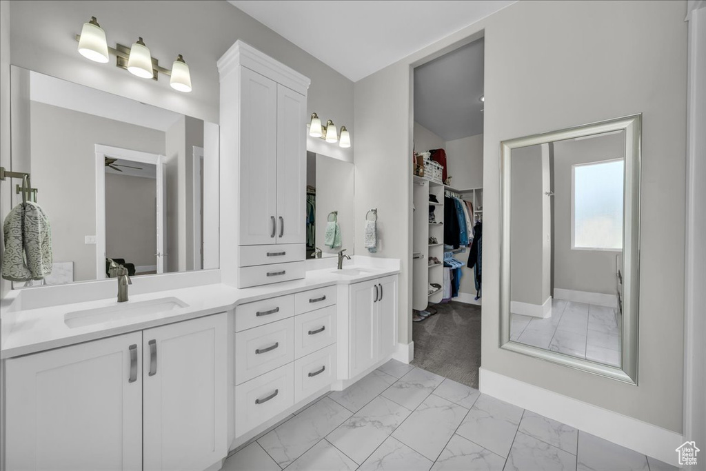 Bathroom with marble look tile flooring, double vanity, and a walk in closet