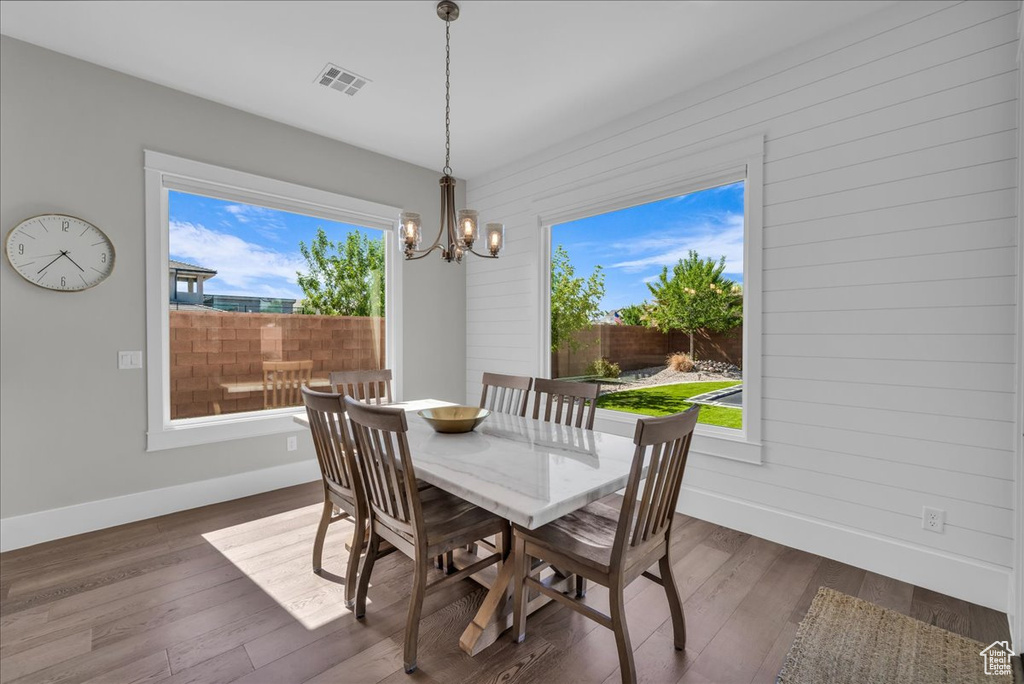 Dining space featuring healthy amount of natural light, a chandelier, and dark wood-style floors
