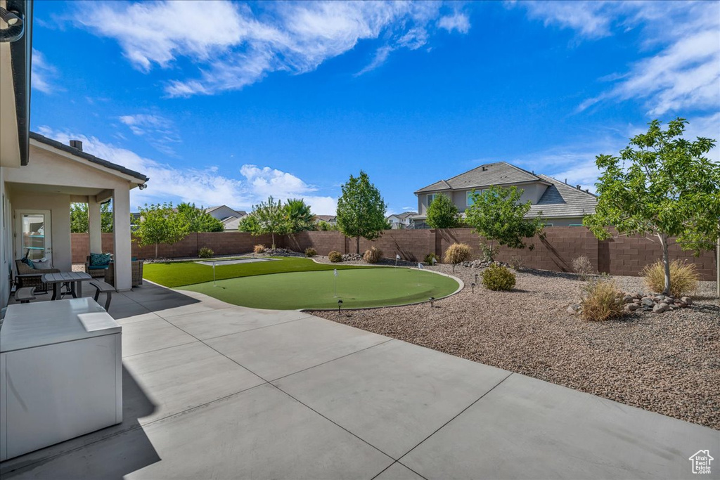 Fenced backyard with a putting area and a patio area