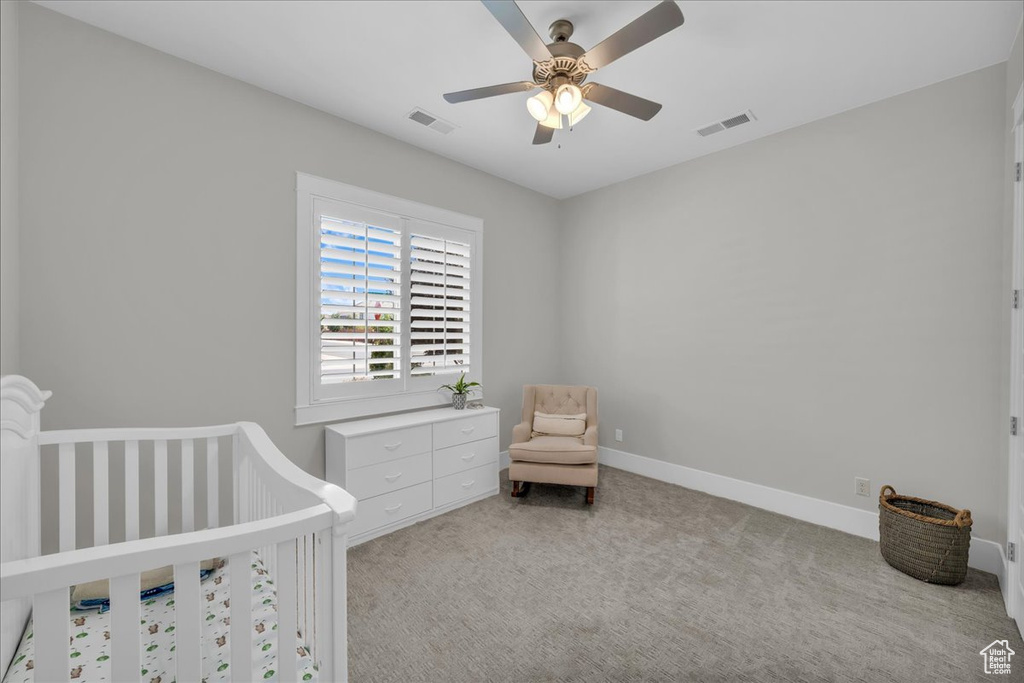 Bedroom featuring carpet floors, ceiling fan, and a nursery area