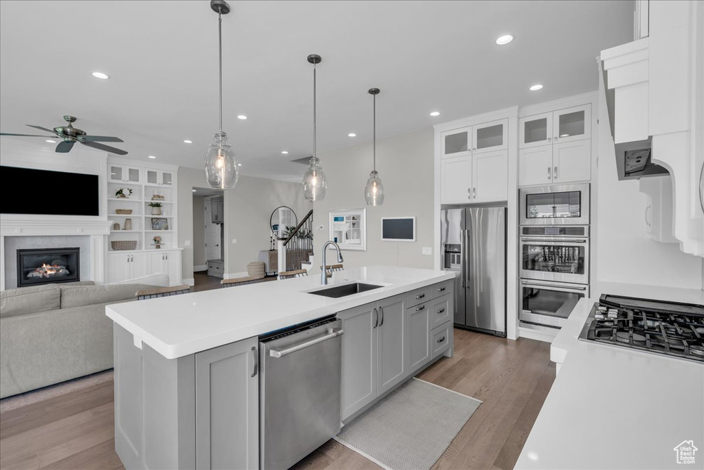Kitchen featuring appliances with stainless steel finishes, ceiling fan, light countertops, an island with sink, and recessed lighting