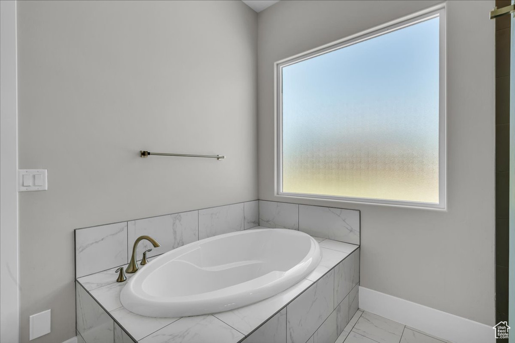 Full bathroom featuring a bath and marble look tiles