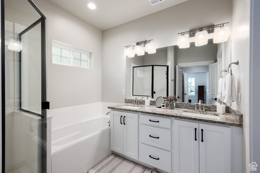 Bathroom featuring a shower stall, a garden tub, double vanity, and recessed lighting
