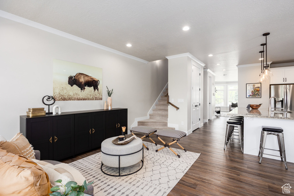 Living room featuring recessed lighting, stairway, dark wood finished floors, and ornamental molding