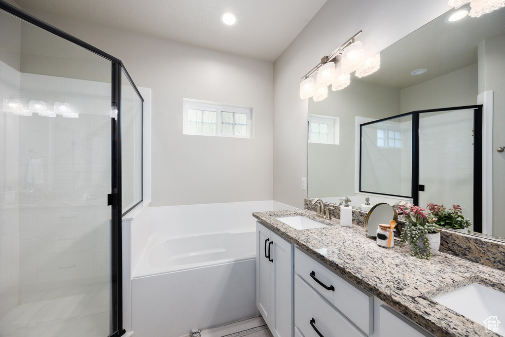 Bathroom with double vanity, a stall shower, a garden tub, and recessed lighting