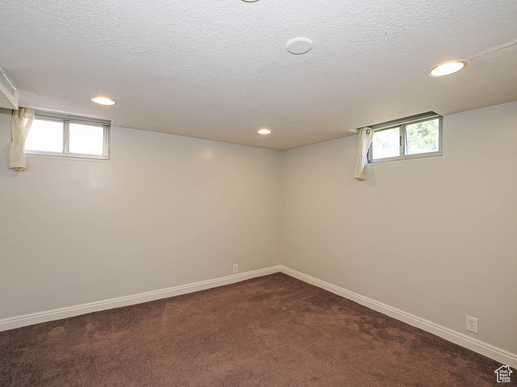 Below grade area featuring recessed lighting, dark carpet, plenty of natural light, and a textured ceiling