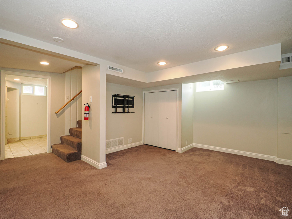 Basement with carpet floors, healthy amount of natural light, stairs, recessed lighting, and a textured ceiling