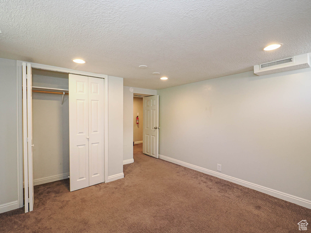 Unfurnished bedroom featuring recessed lighting, carpet floors, a closet, and a textured ceiling