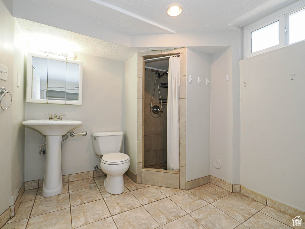 Full bathroom featuring tiled shower, a textured ceiling, and tile patterned floors