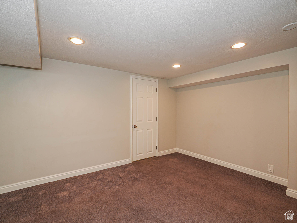 Finished below grade area featuring dark colored carpet, recessed lighting, and a textured ceiling