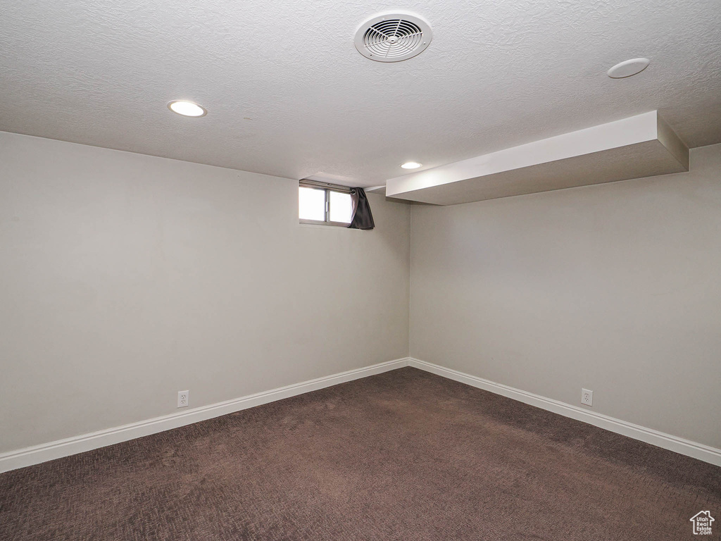 Basement featuring dark carpet, recessed lighting, and a textured ceiling