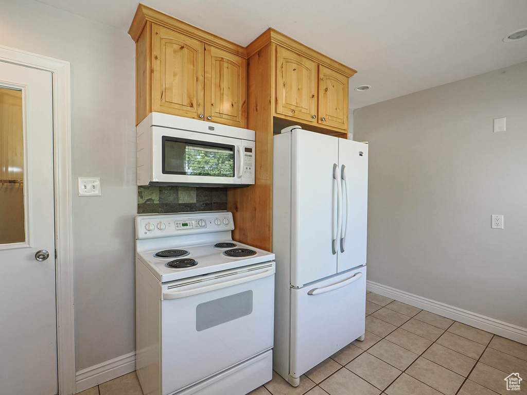 Kitchen with white appliances, tasteful backsplash, and light tile patterned floors