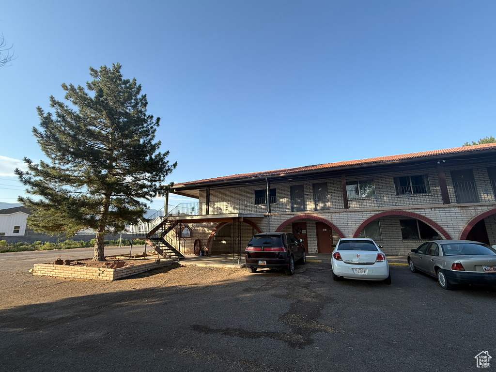 View of front of house featuring stairs, brick siding, and uncovered parking