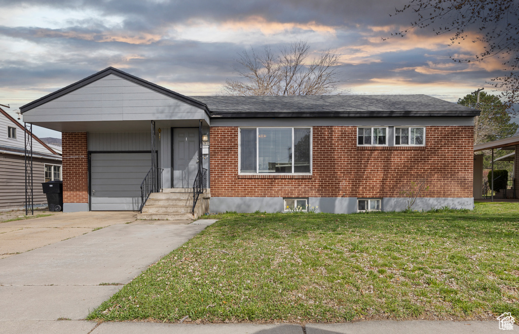 Ranch-style house with brick siding, entry steps, a front lawn, and driveway