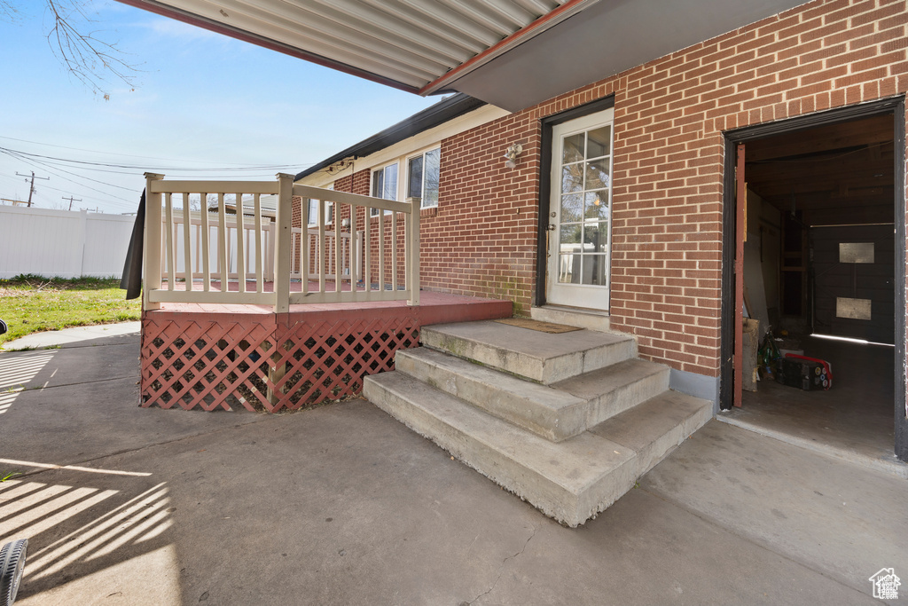 Entrance to property featuring brick siding and a wooden deck