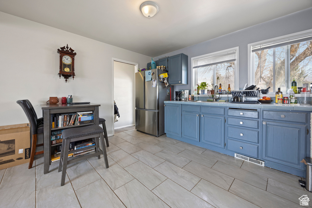 Kitchen with freestanding refrigerator, blue cabinets, and tile counters