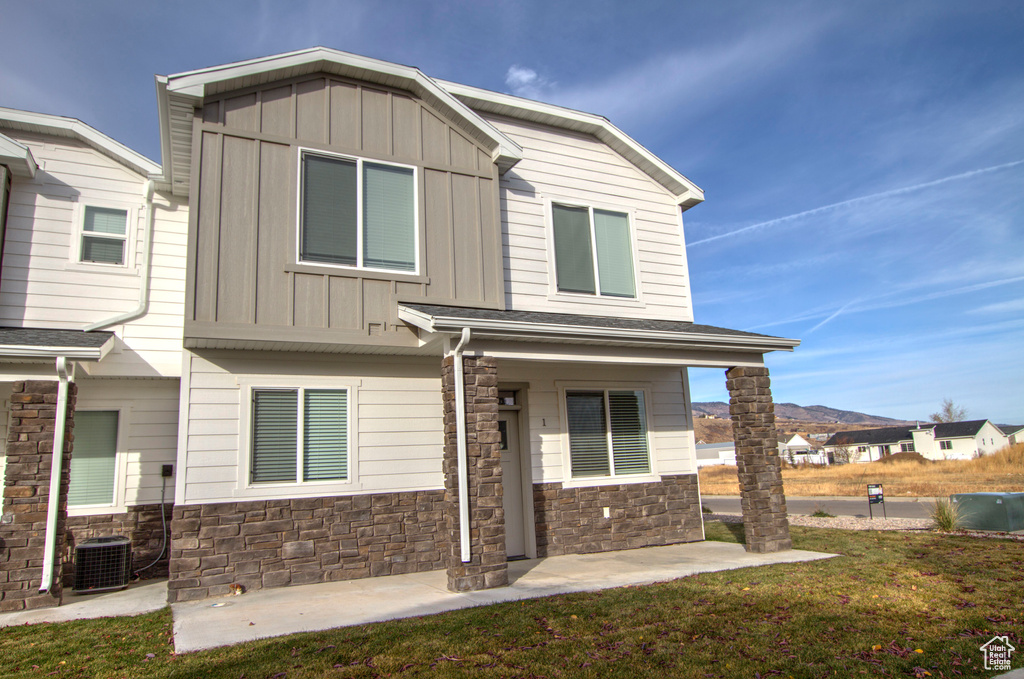 Craftsman-style home featuring board and batten siding, stone siding, a front lawn, and a mountain view
