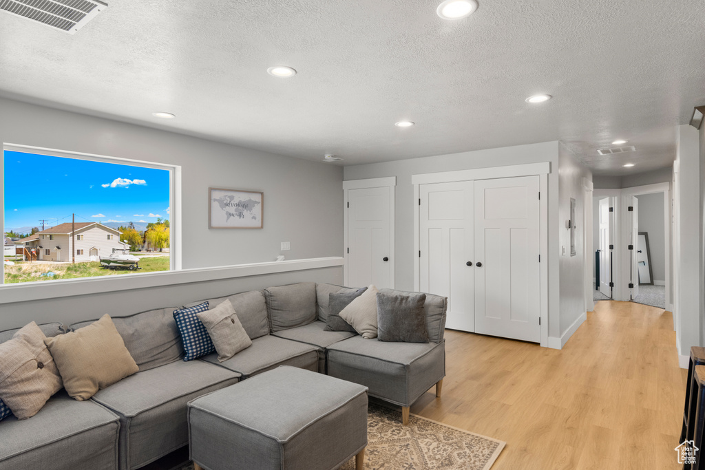 Living area with recessed lighting, light wood-type flooring, and a textured ceiling