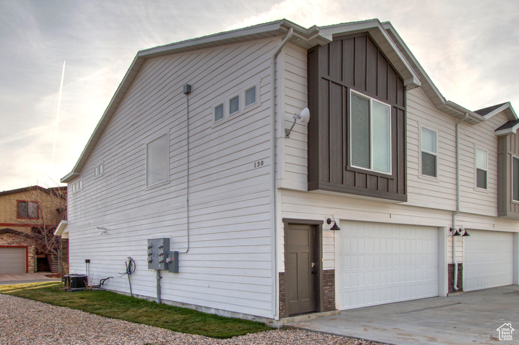 View of side of home with board and batten siding, driveway, and a garage