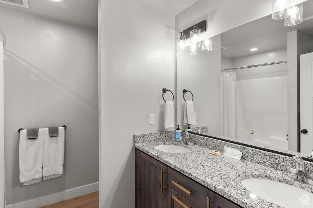 Bathroom with double vanity, a shower with curtain, and wood finished floors