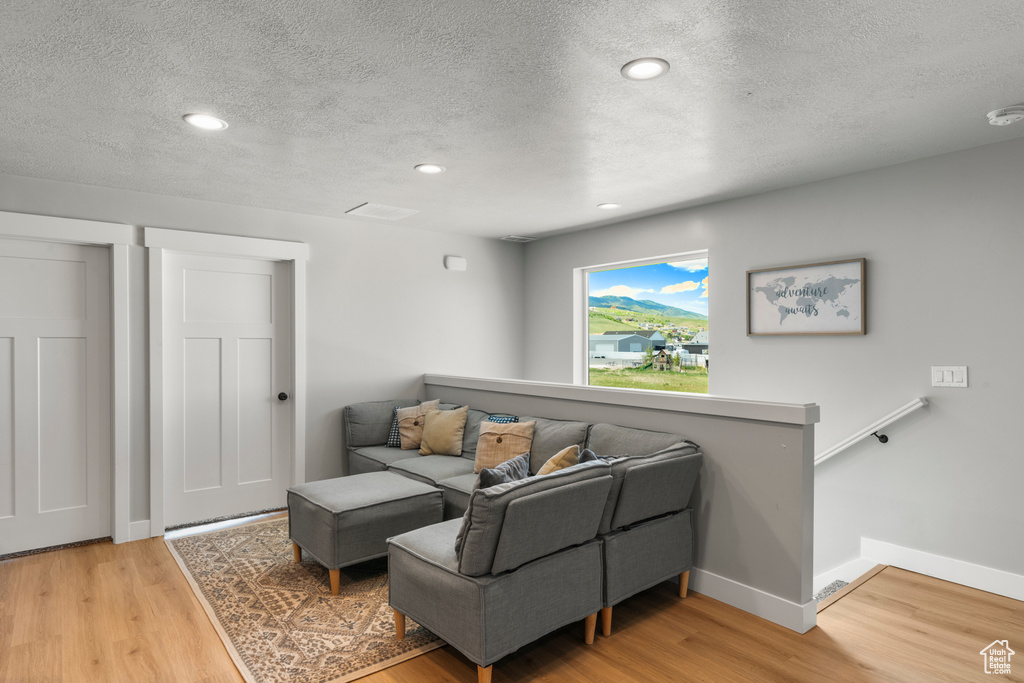 Living room featuring a textured ceiling, light wood finished floors, and recessed lighting