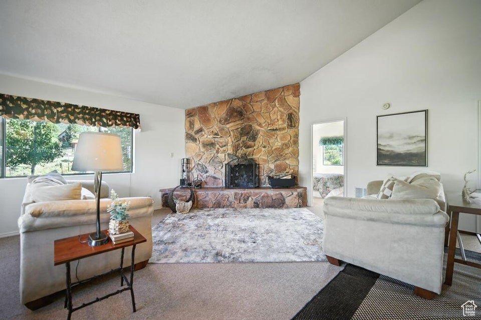 Carpeted living room with plenty of natural light, a fireplace, and high vaulted ceiling