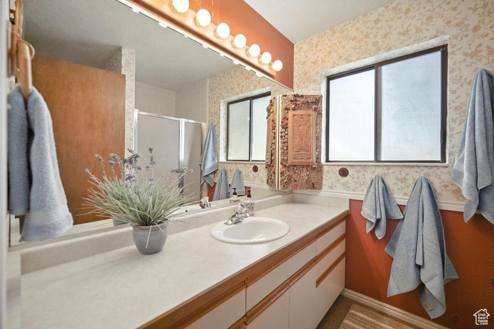 Bathroom featuring wallpapered walls, vanity, plenty of natural light, and a stall shower