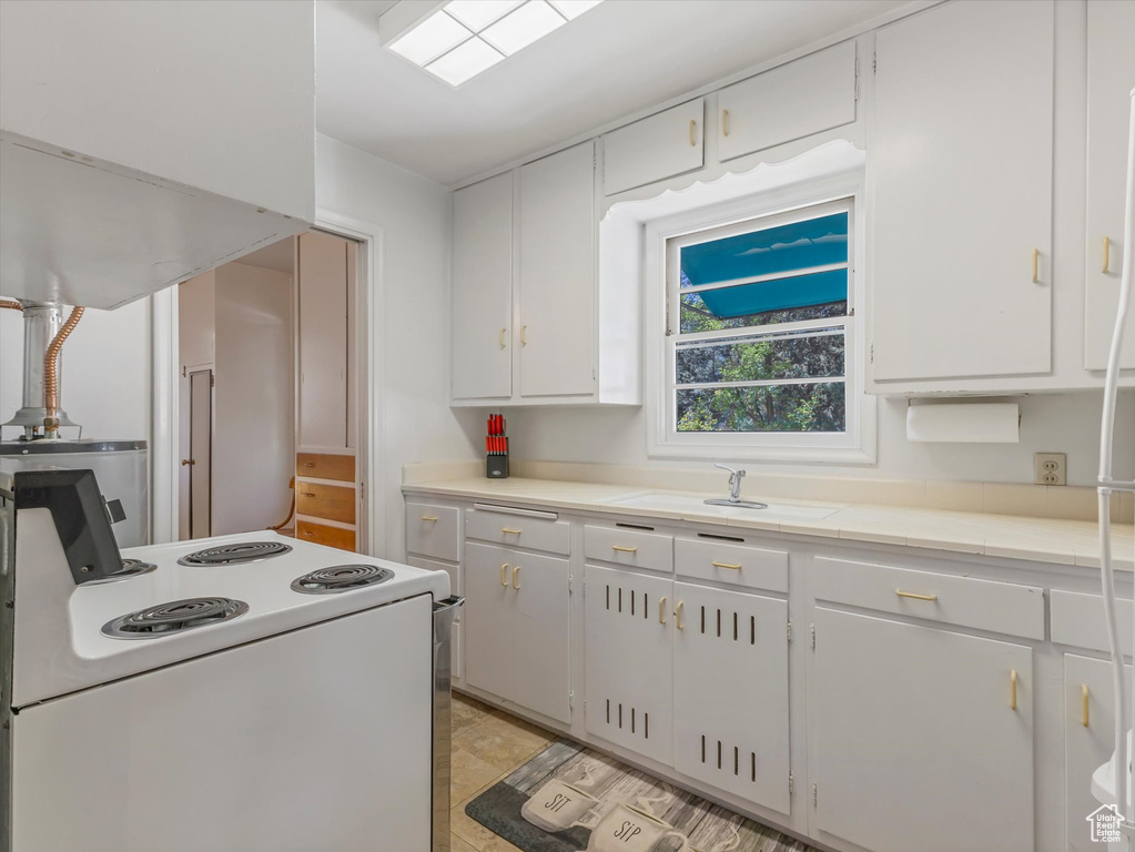 Kitchen featuring white electric range oven, white cabinets, and light countertops
