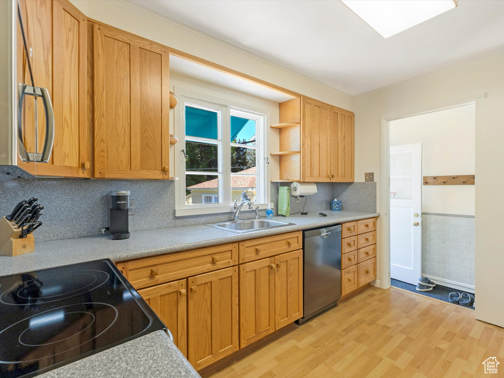 Kitchen with stainless steel dishwasher, light wood-type flooring, light countertops, open shelves, and tasteful backsplash
