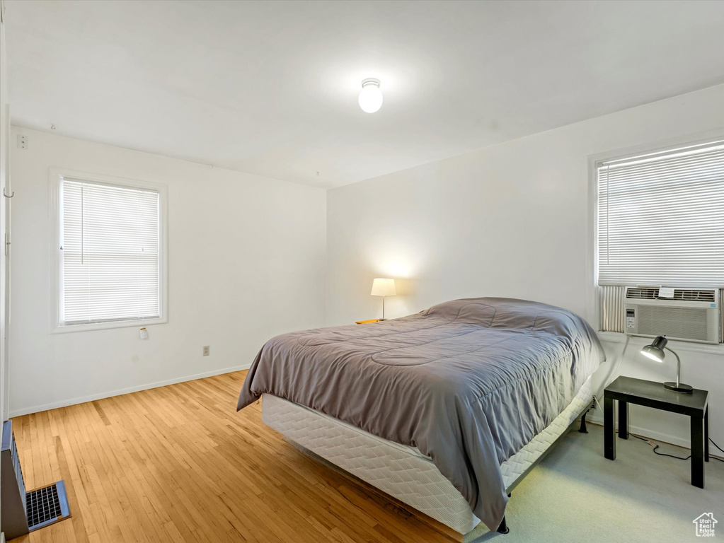 Bedroom with cooling unit and wood finished floors