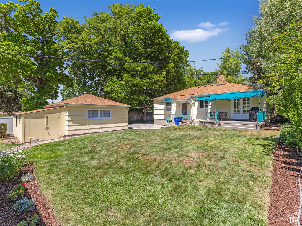 View of yard featuring french doors, a patio, and an outbuilding