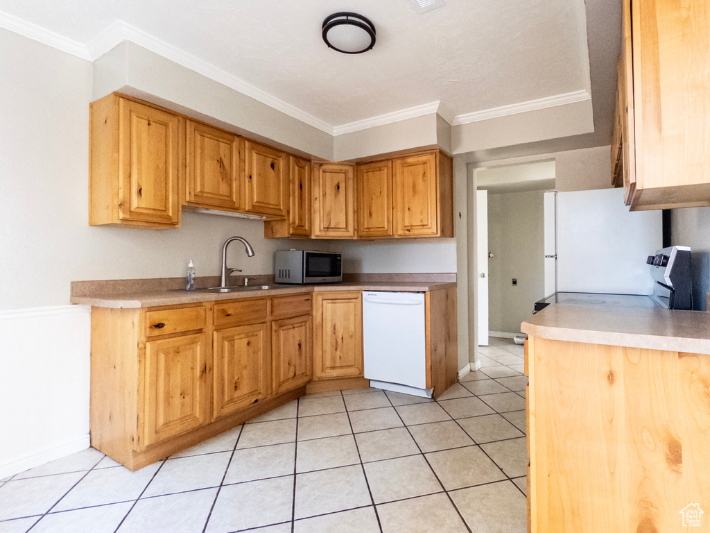 Kitchen featuring white dishwasher, stainless steel microwave, ornamental molding, light tile patterned floors, and light countertops