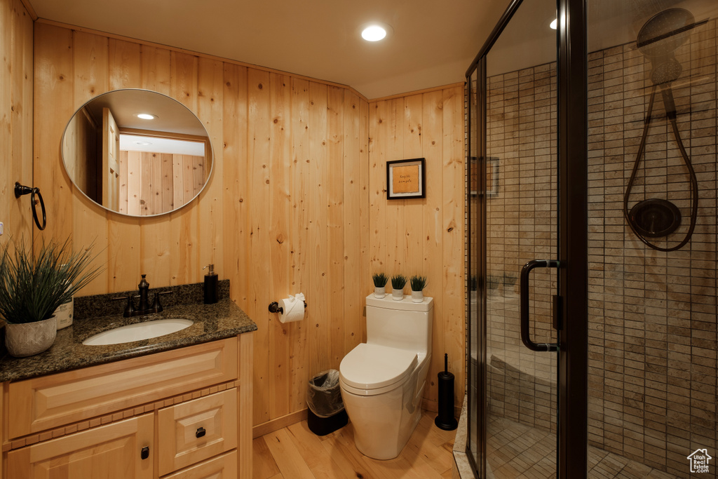 Bathroom with vanity, wood finished floors, a stall shower, wooden walls, and recessed lighting