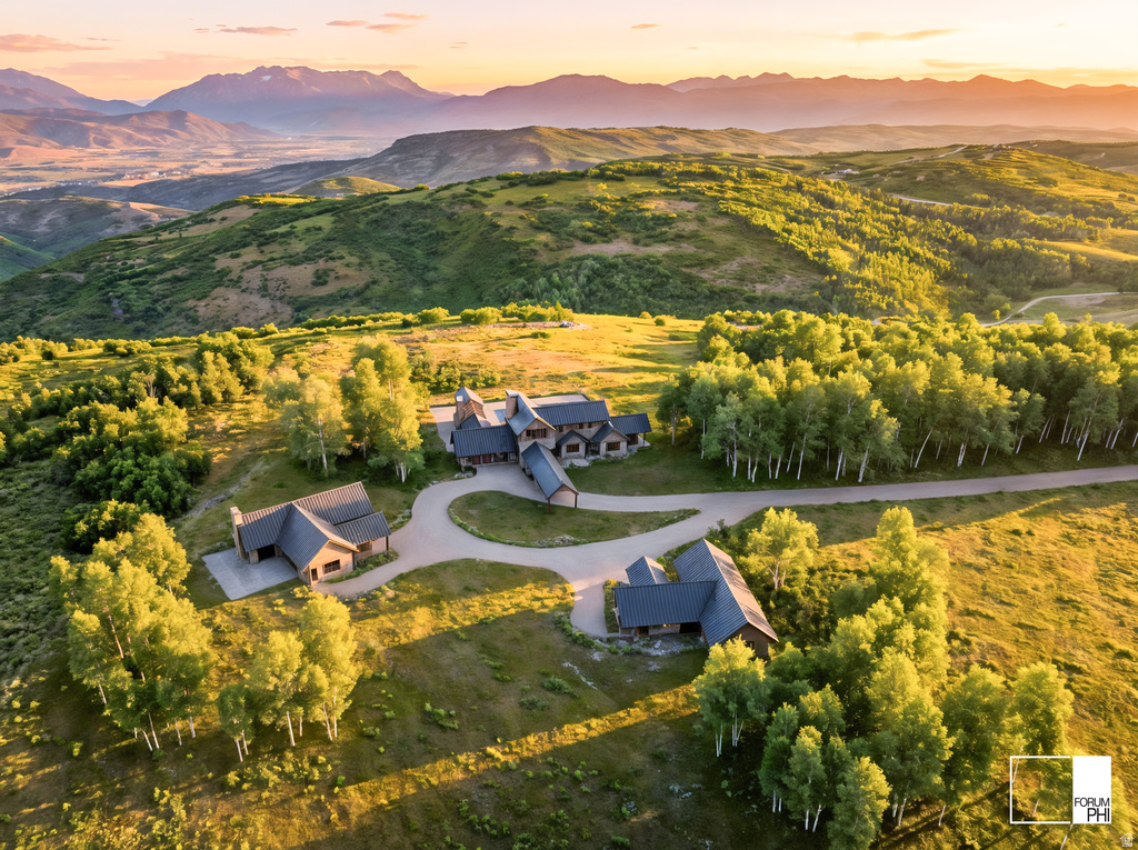 Expansive property featuring multiple structures, a circular driveway, and surrounding natural landscaping