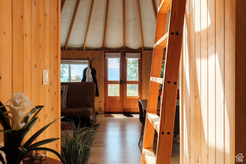 Living area with wood-type flooring, french doors, and wooden walls