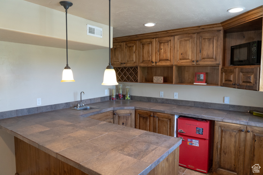 Kitchen featuring open shelves, black microwave, a peninsula, brown cabinets, and recessed lighting