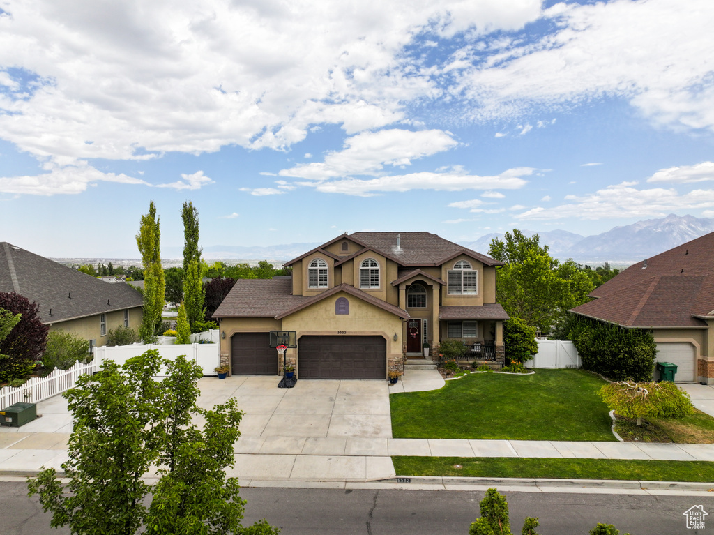 Traditional-style home featuring stucco siding, driveway, an attached garage, stone siding, and roof with shingles