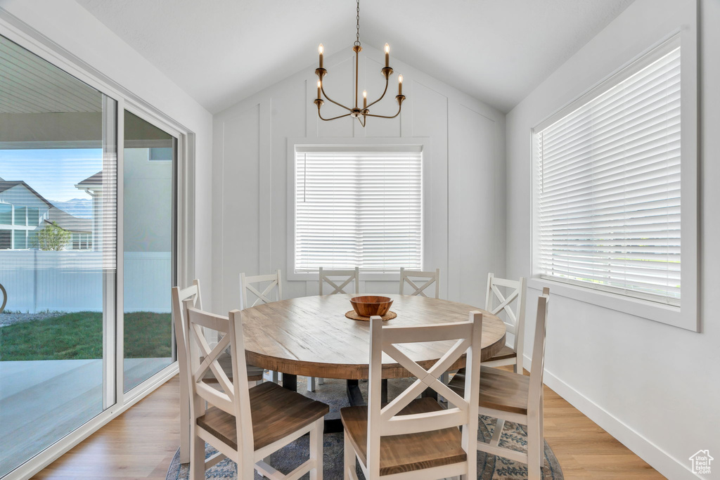 Dining space with light wood-style floors, a chandelier, and vaulted ceiling