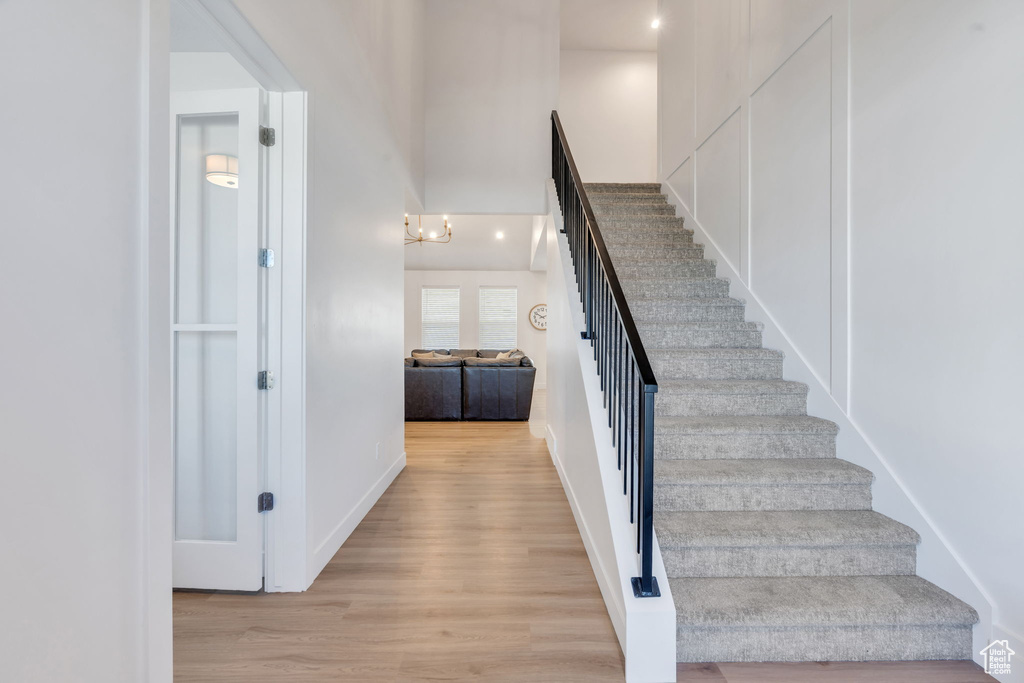Staircase featuring wood finished floors and a chandelier