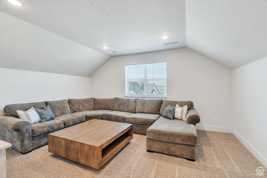 Living area with vaulted ceiling, light carpet, recessed lighting, and a textured ceiling