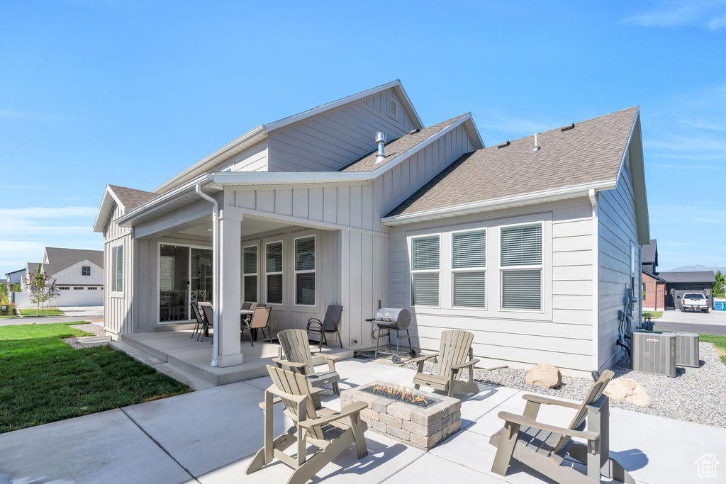 Rear view of property featuring an outdoor fire pit, a patio, board and batten siding, and a shingled roof