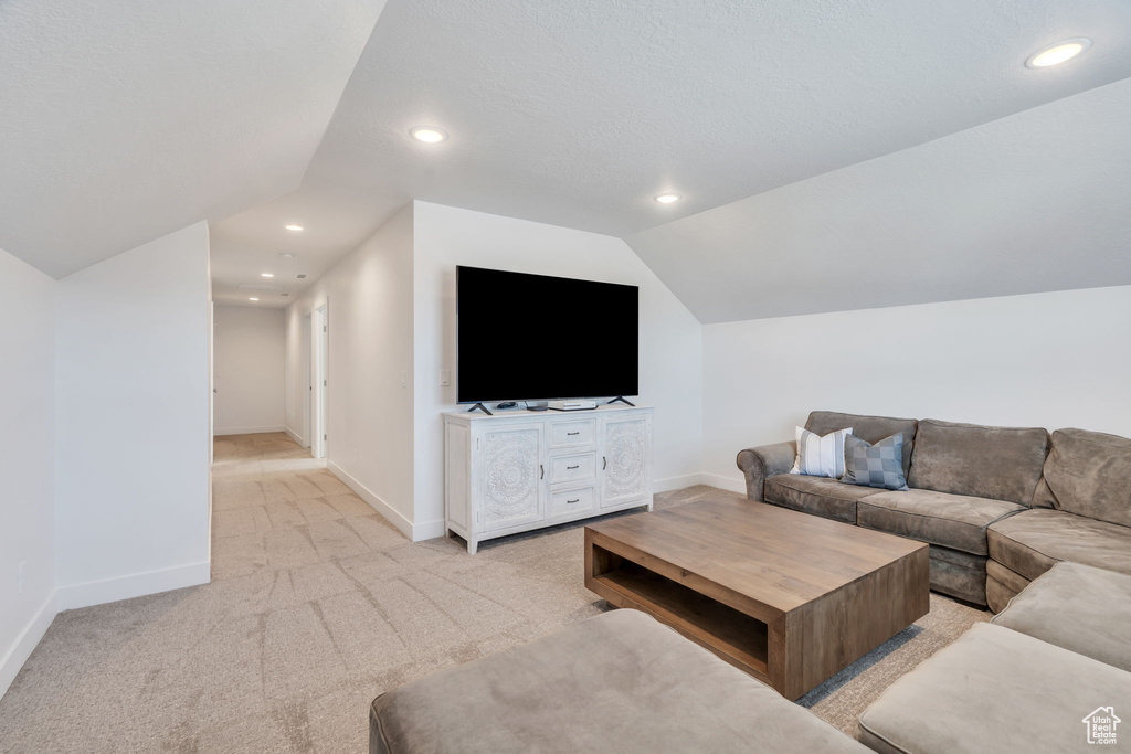 Carpeted living room with vaulted ceiling and recessed lighting