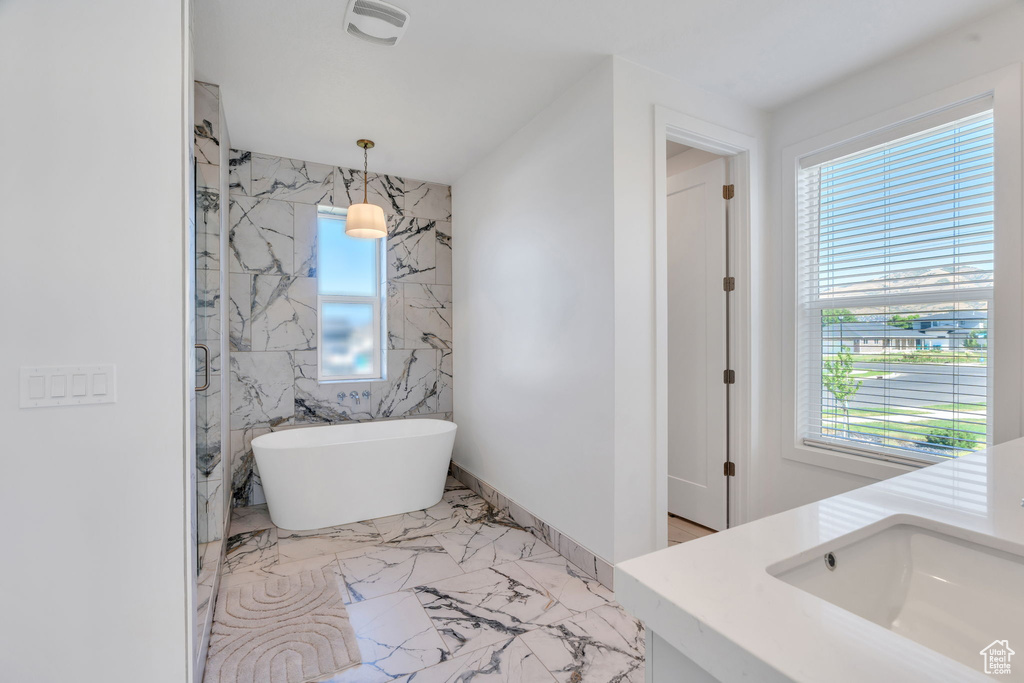 Full bath with plenty of natural light, a soaking tub, and vanity