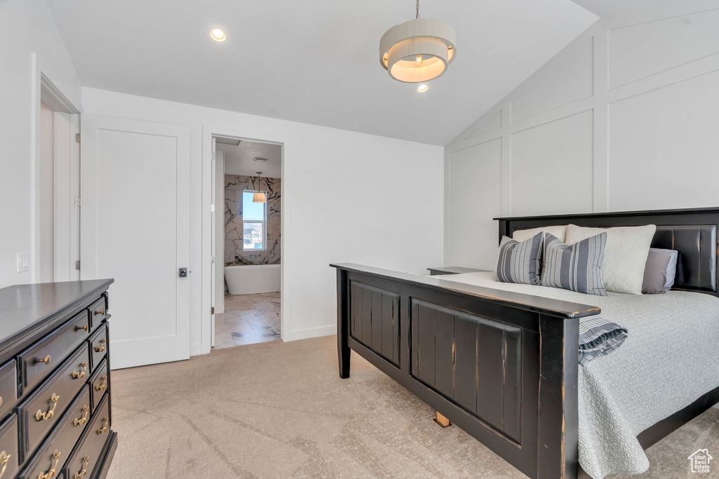 Bedroom with vaulted ceiling, ensuite bath, and light carpet